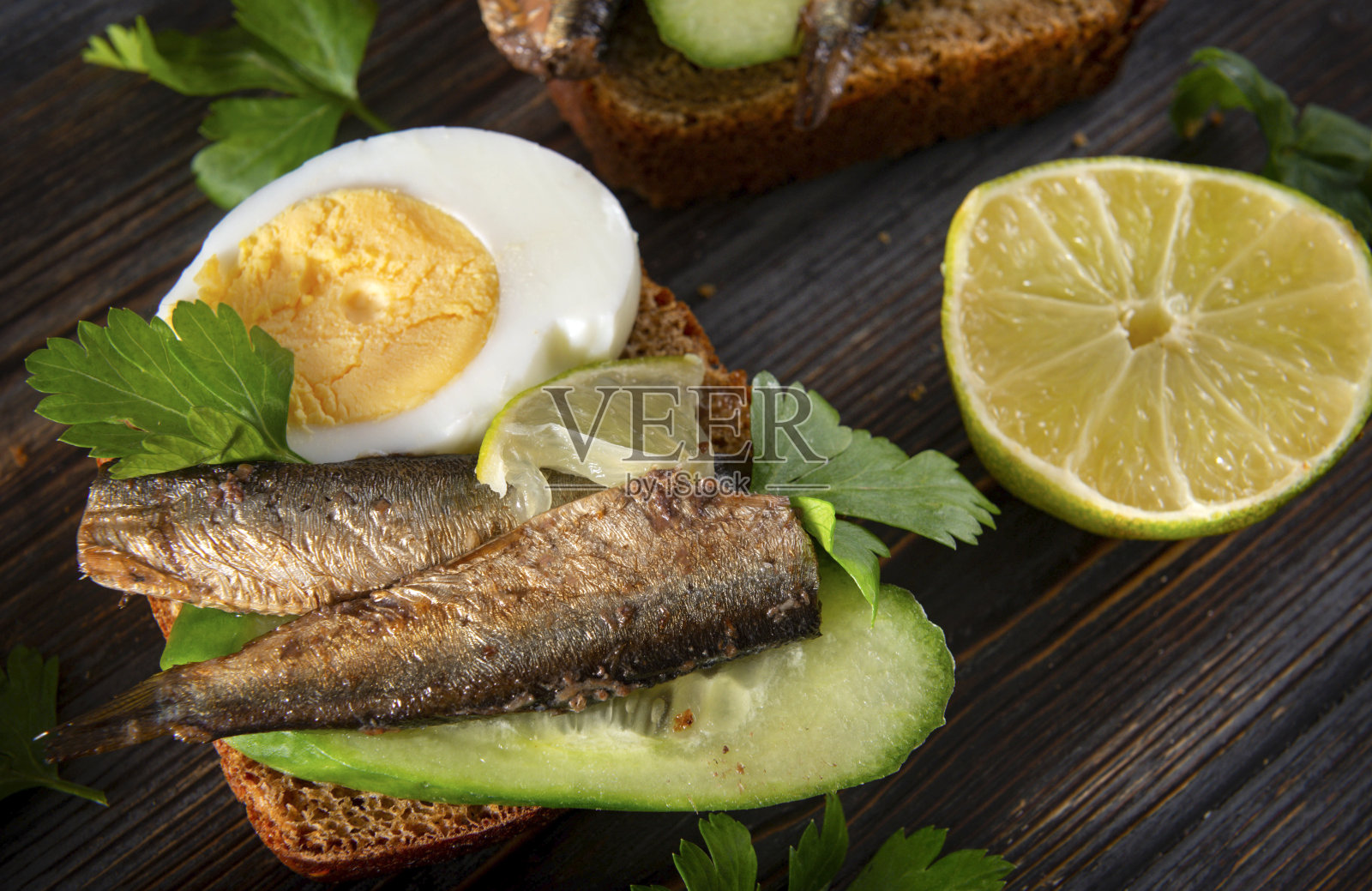 三明治配鲱鱼，酸橙，新鲜黄瓜，黑麦面包，欧芹，鸡蛋，罐头鱼，照片摄影图片