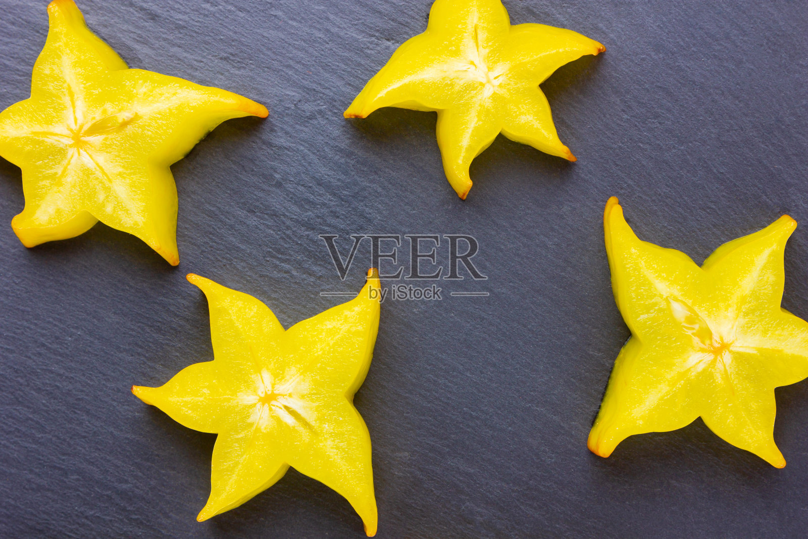 深色背景上的杨桃。切片的杨桃在黑色的背景上。杨桃片。时尚的食物照片摄影图片