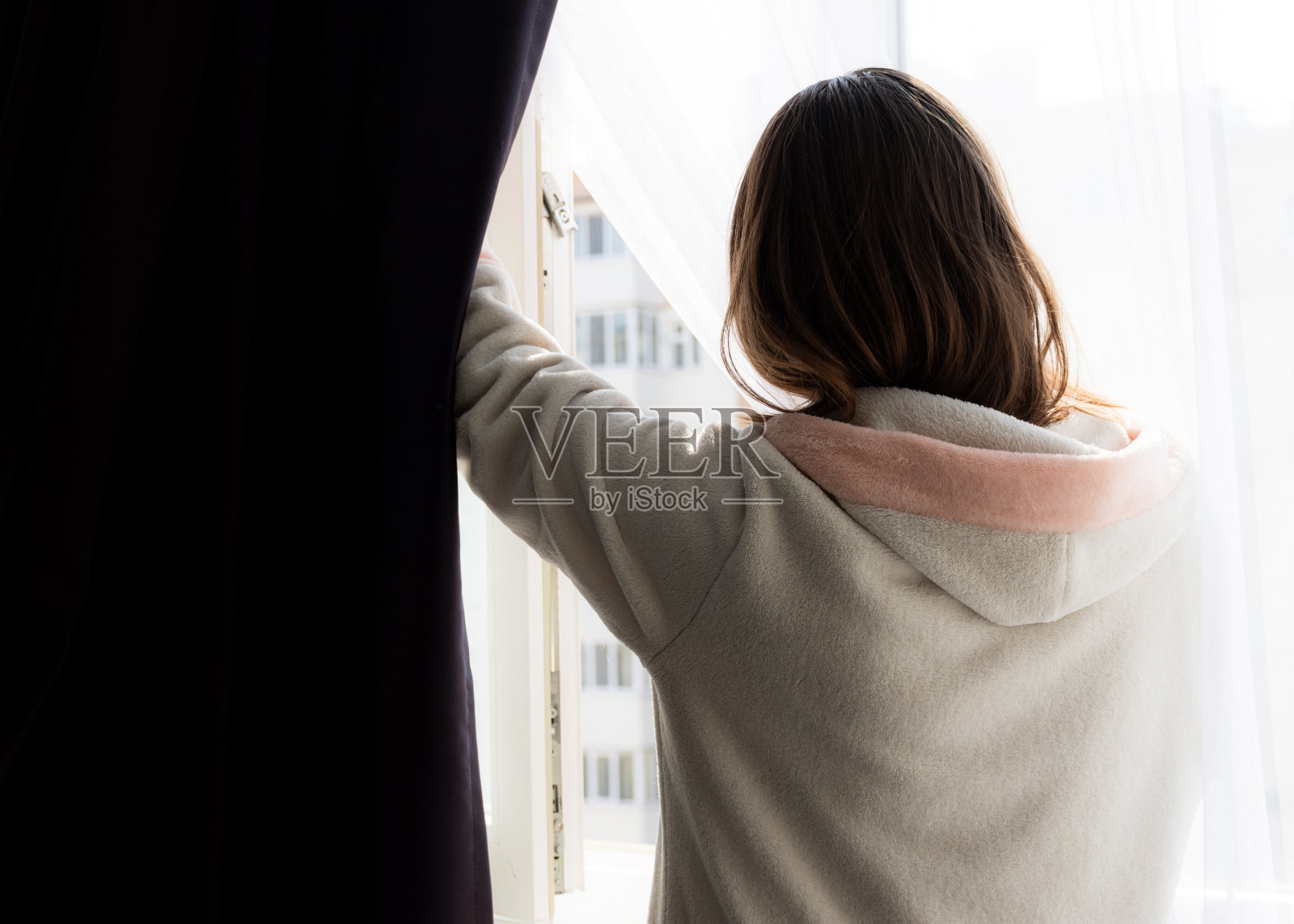 与冠状病毒隔离的女孩。家里的女孩打开窗户晾晒空气。照片摄影图片