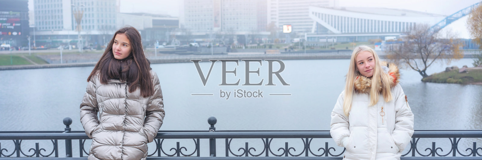 穿着暖和外套的少女们正站在公园里照片摄影图片