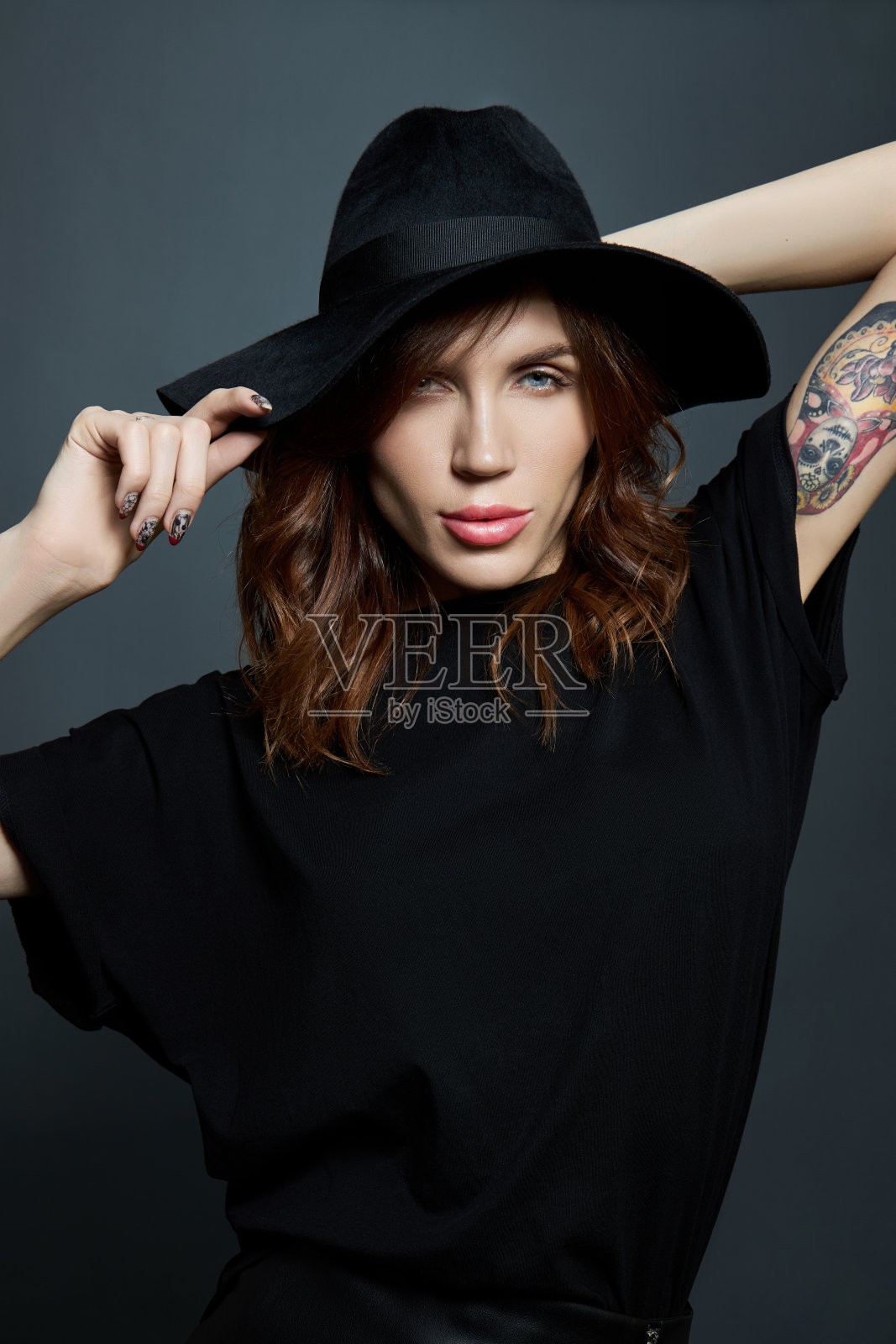 一个女人的肖像，戴着一顶大的黑帽子，背景是黑色的照片摄影图片