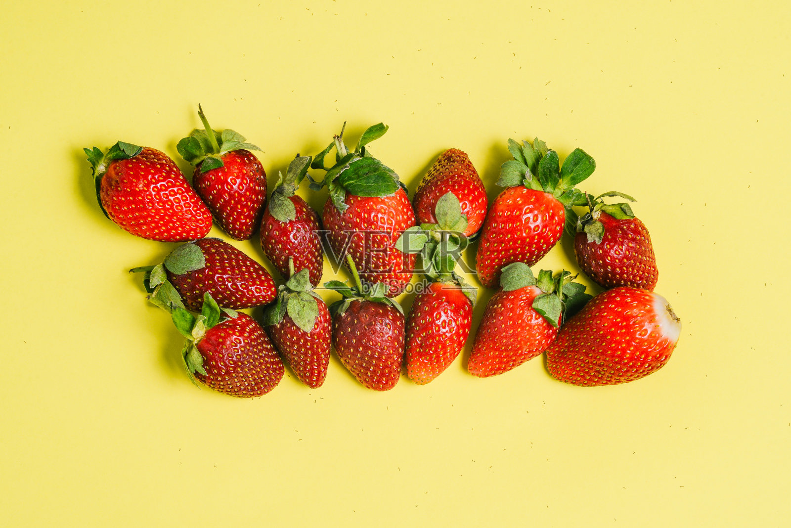 新鲜的草莓和绿色的叶子在一个彩色的背景。美味的夏日浆果。烘焙、酸奶、鸡尾酒的配料。水果的背景。照片摄影图片