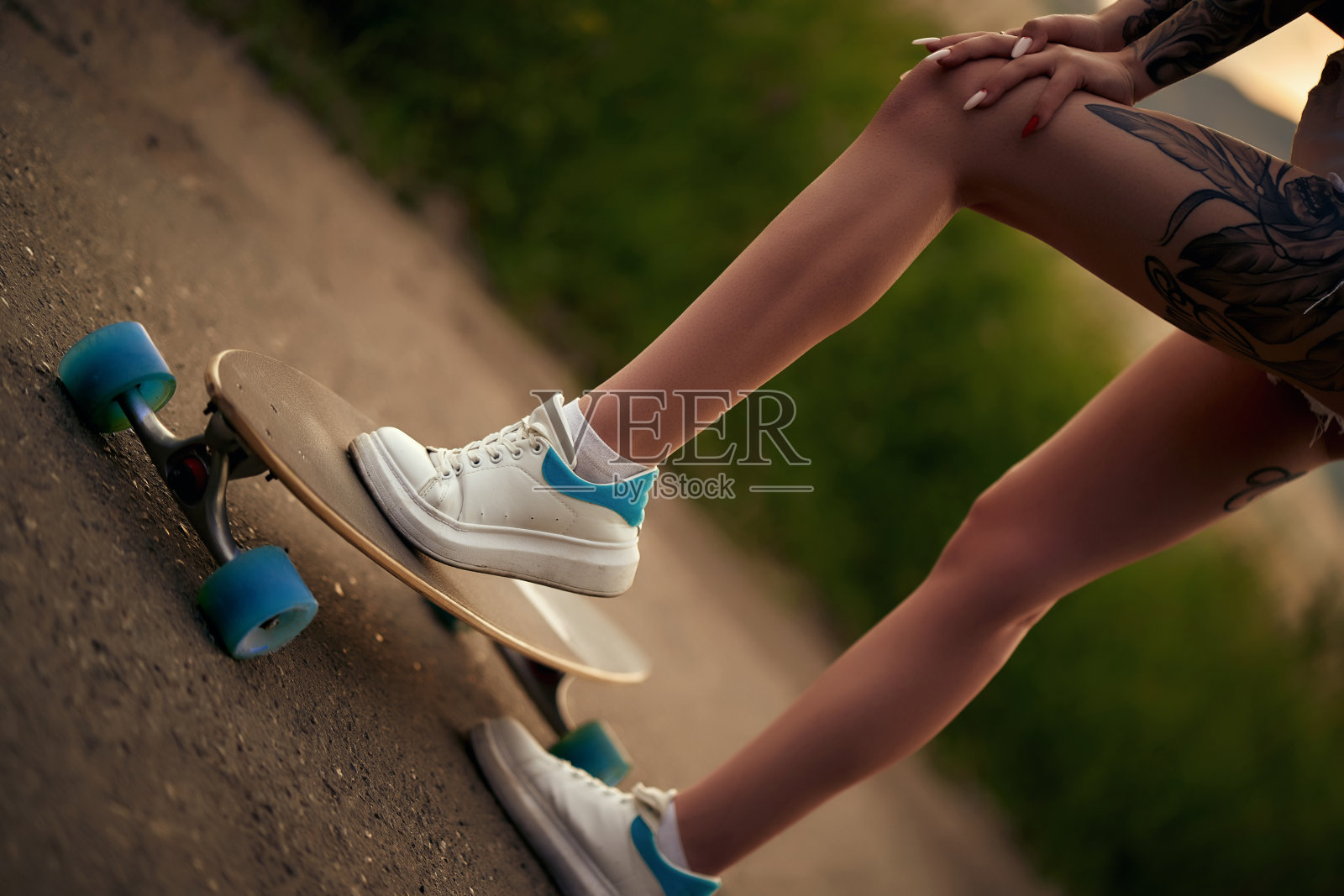 时髦女孩，胳膊和腿上都有纹身，还有一双蓝眼睛。骑冲浪老手照片摄影图片