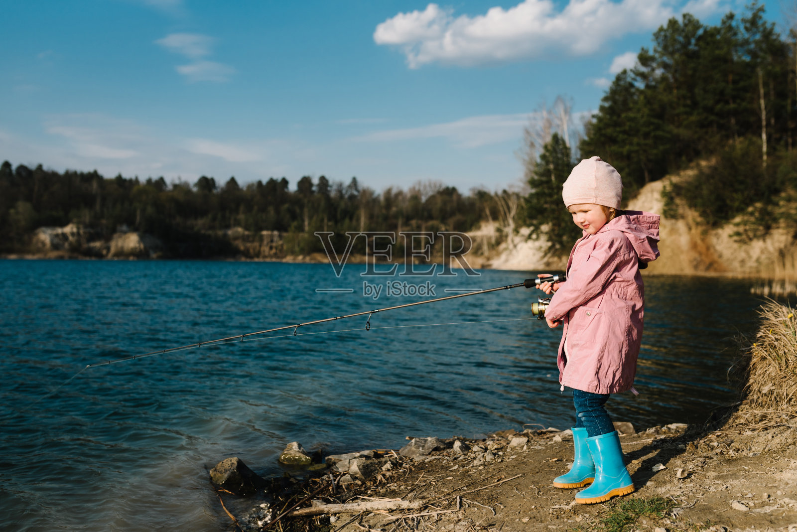 孤独快乐的小孩从海滩、湖泊或池塘钓鱼与文字空间。小女孩抓了一条鱼。孩子们在周末钓鱼时拉杆的照片。照片摄影图片