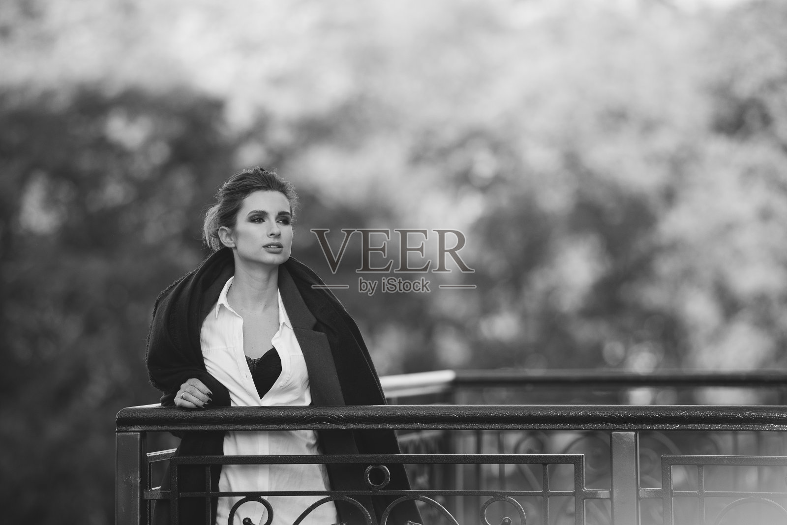 在一个阴冷的日子里，一个美丽的孤独的女人在桥上，她的头发在风中飘动，嘴唇丰满。黑白艺术照片。软选择聚焦。照片摄影图片