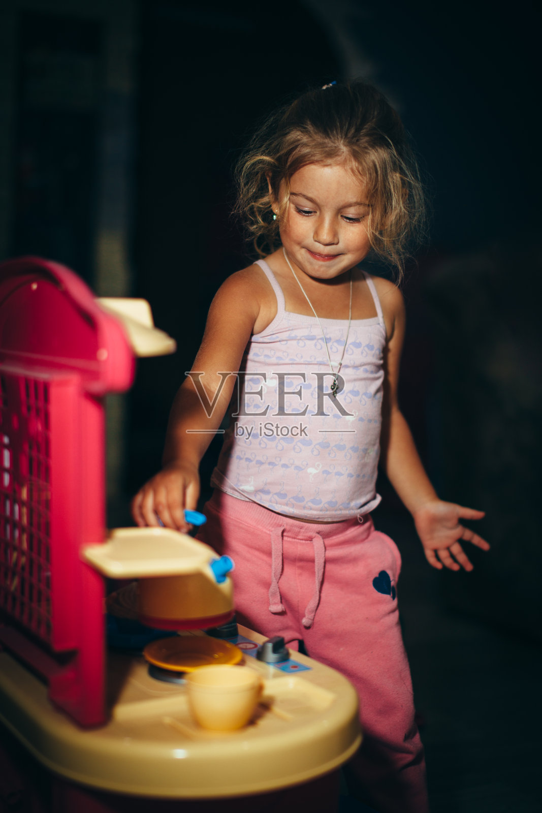 快乐的小女孩在玩玩具厨房照片摄影图片