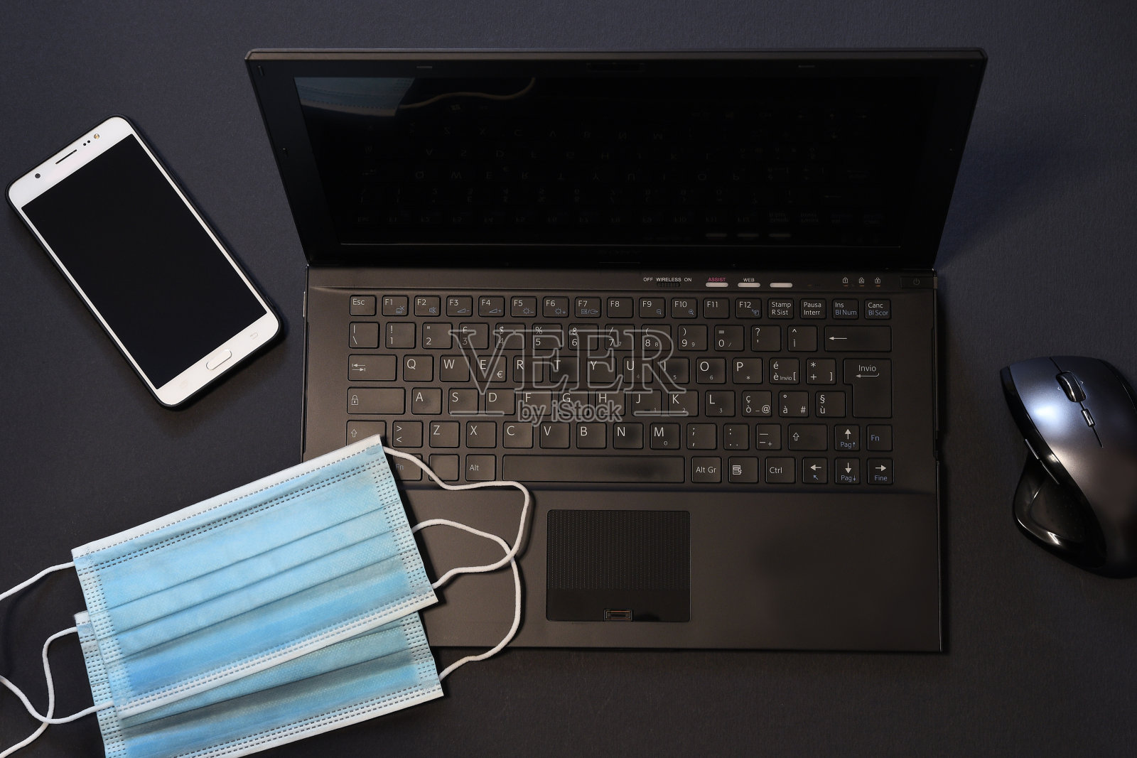 医用蓝色冠状病毒防护口罩，笔记本电脑键盘、鼠标和智能手机。呆在家里工作。智慧工作的概念。照片摄影图片