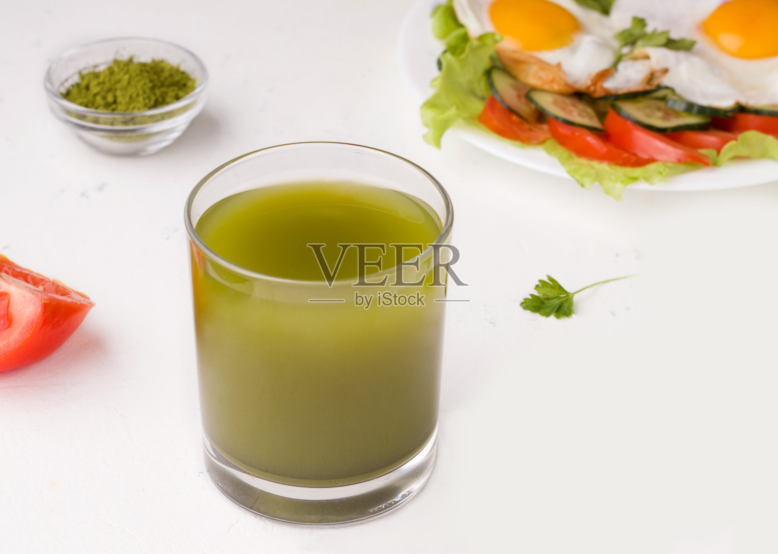 抹茶绿茶在白色的背景旁边炒鸡蛋和蔬菜。健康的早餐概念照片摄影图片