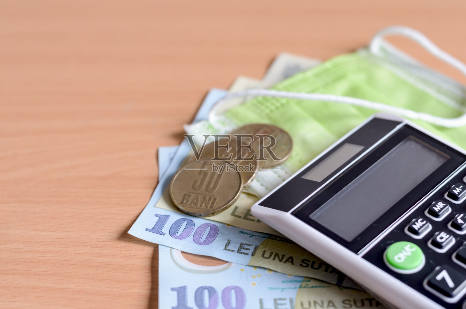 特写罗马尼亚雷和医用一次性口罩手持微型计算器在木制背景。冠状病毒对东欧国家的经济影响。照片摄影图片