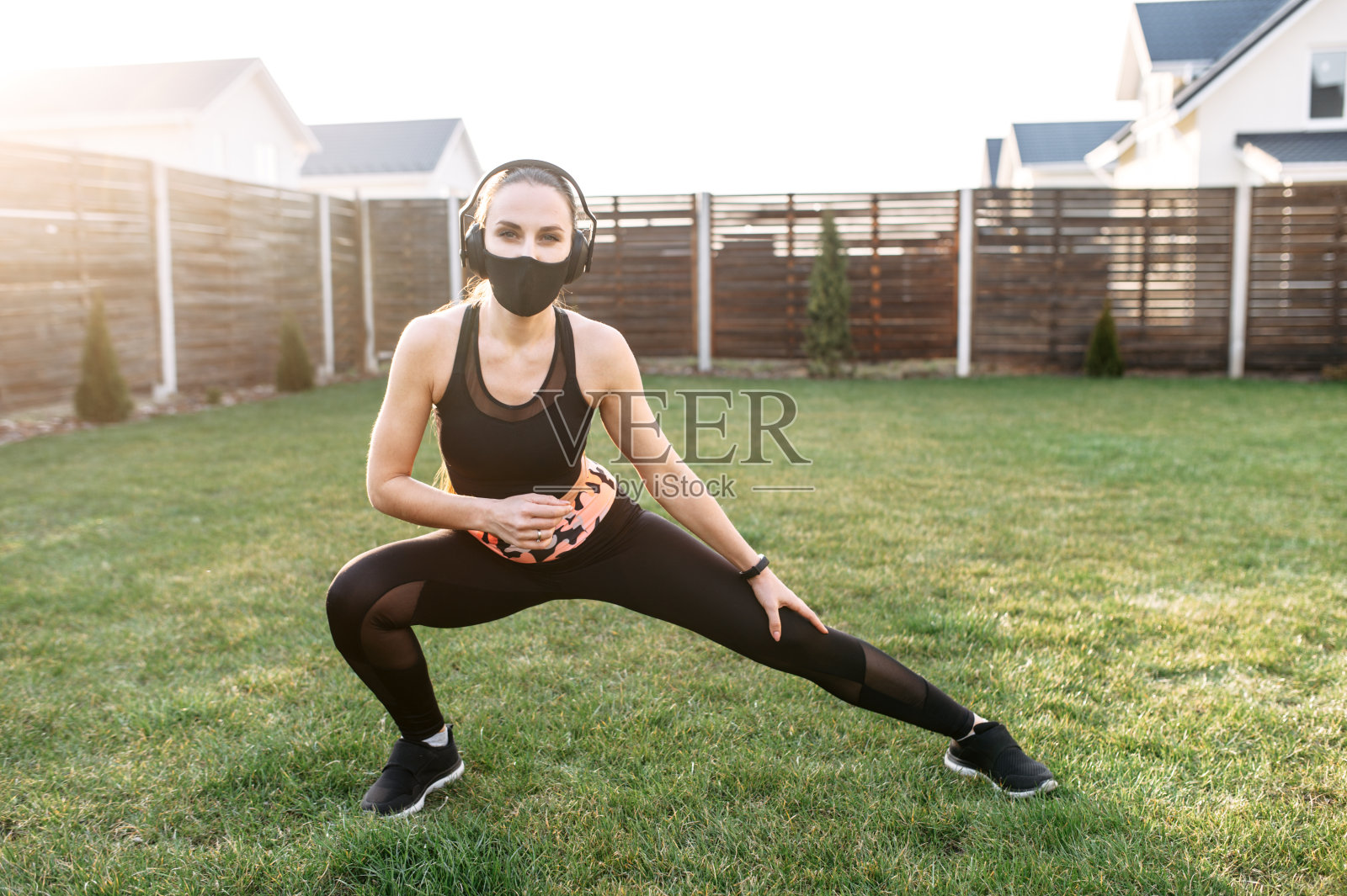 戴面具的女人在后院做伸展运动照片摄影图片