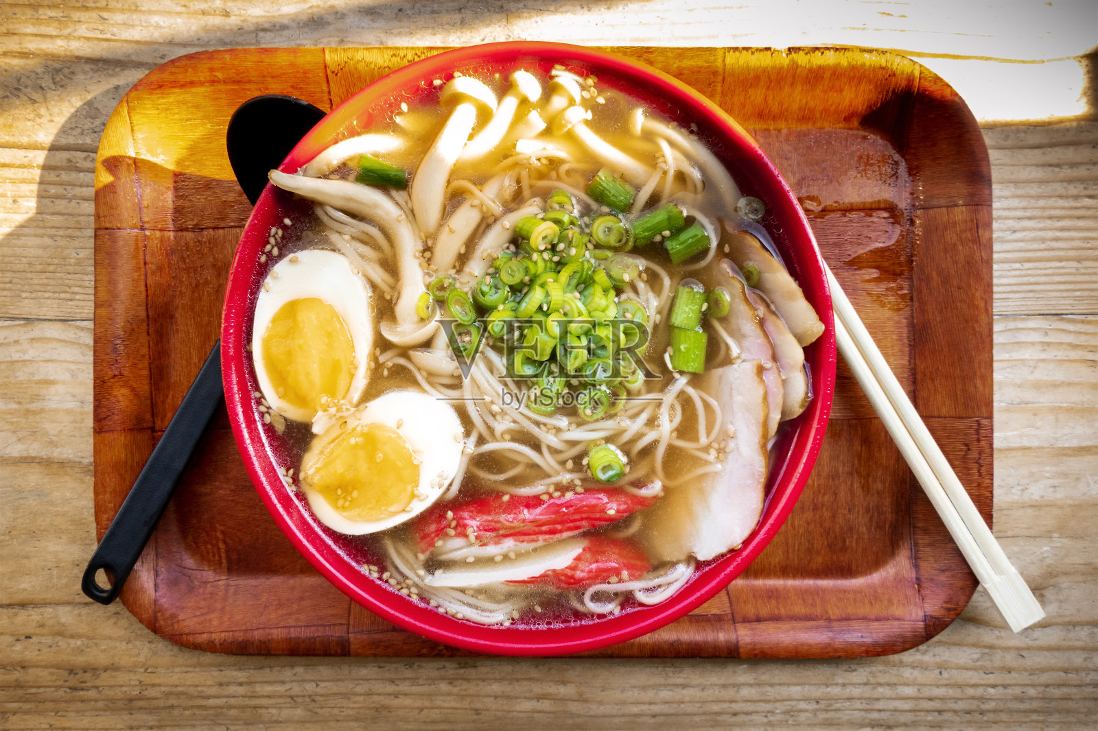 Tonkotsu拉面特写，从上往下拍摄，里面有鸡蛋、葱和蘑菇，托盘上放着筷子照片摄影图片