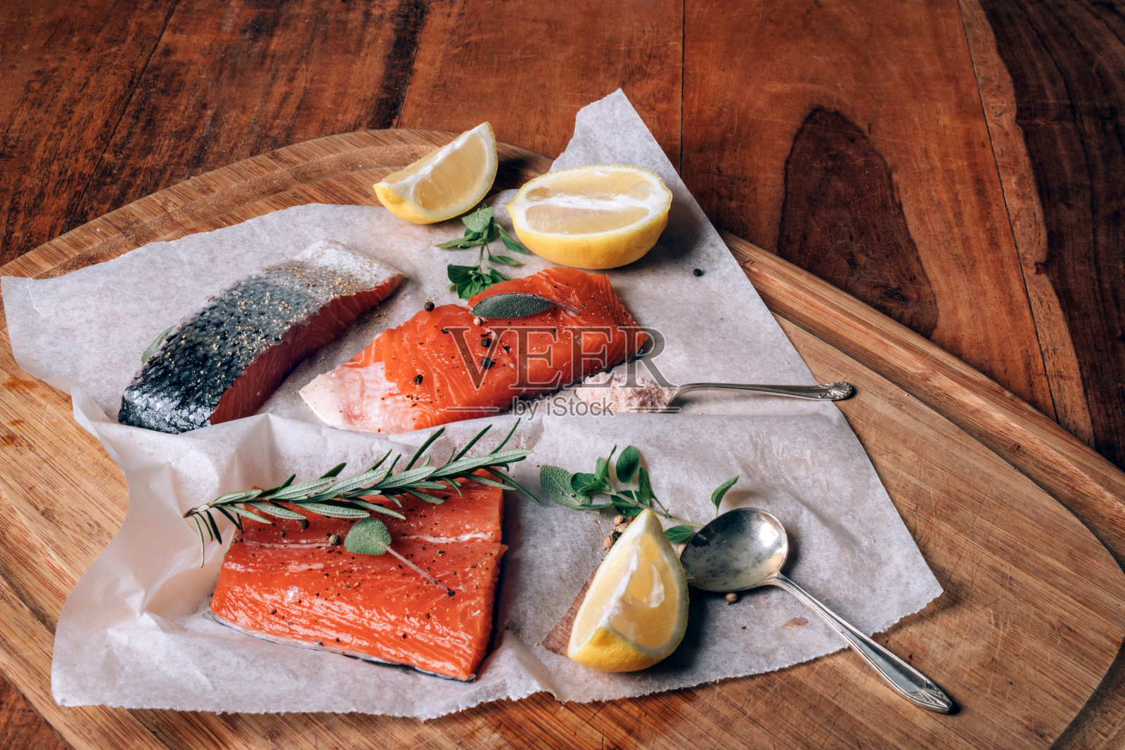 切板上的纸上印着新鲜的生鲑鱼，配上柠檬、香草和香料照片摄影图片