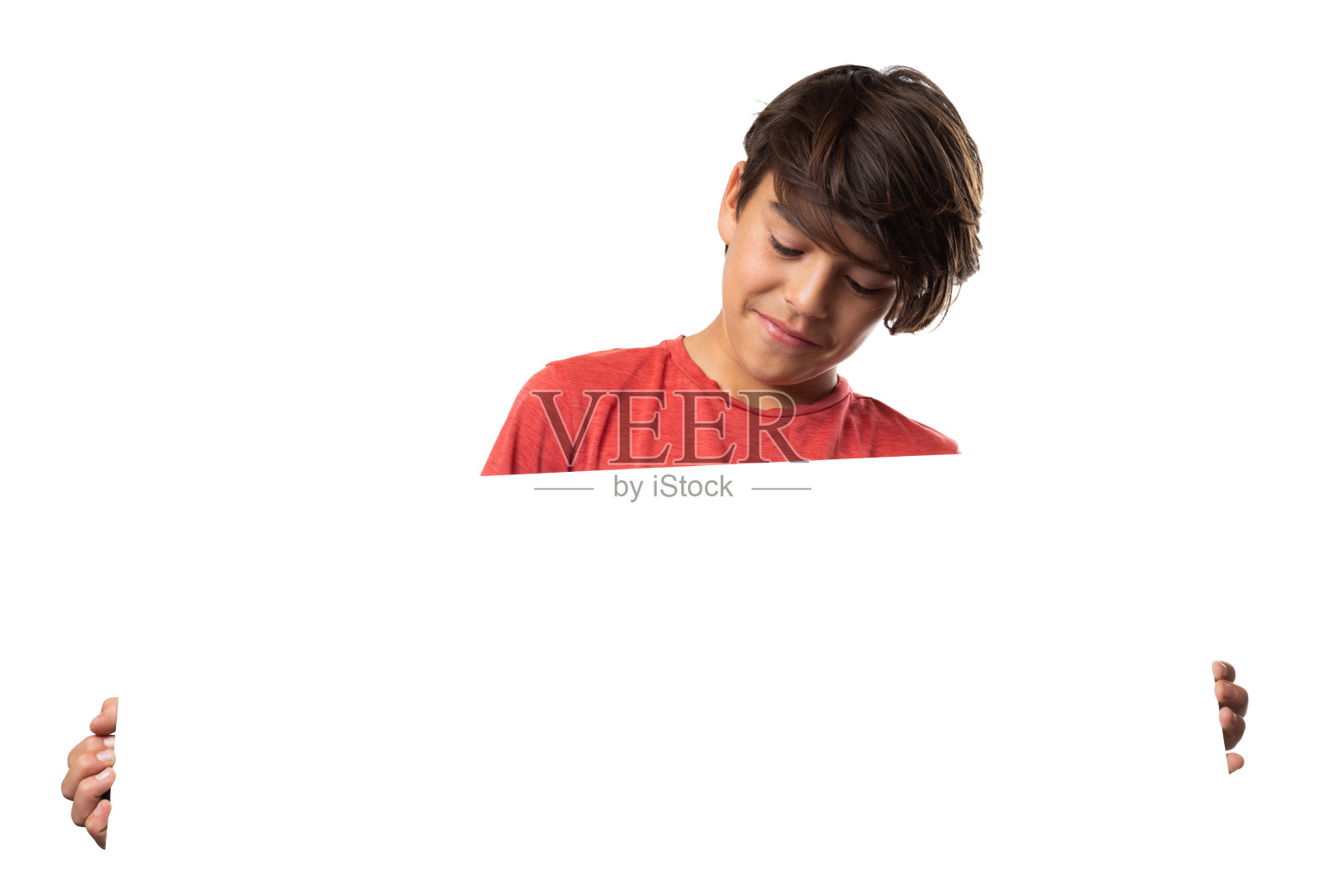 可爱的男孩微笑，抱着和看着空白标志，在白色的背景照片摄影图片