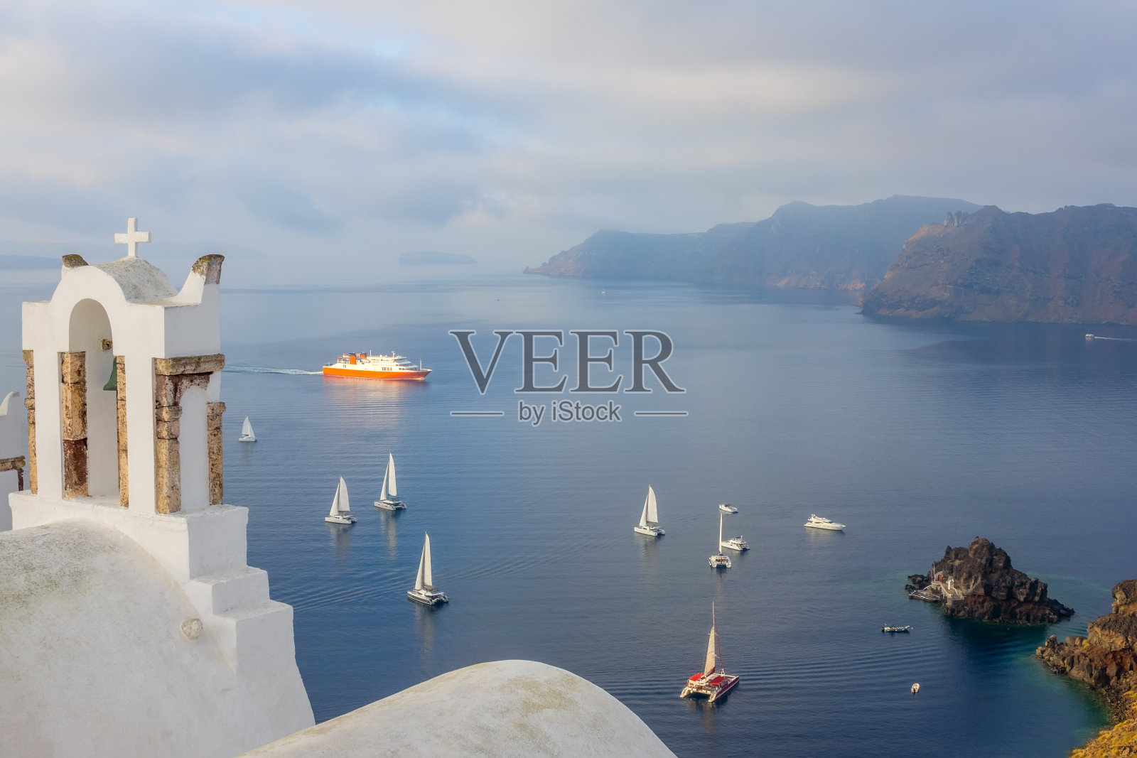 希腊教堂和火山口的十字架，有帆船和游船照片摄影图片