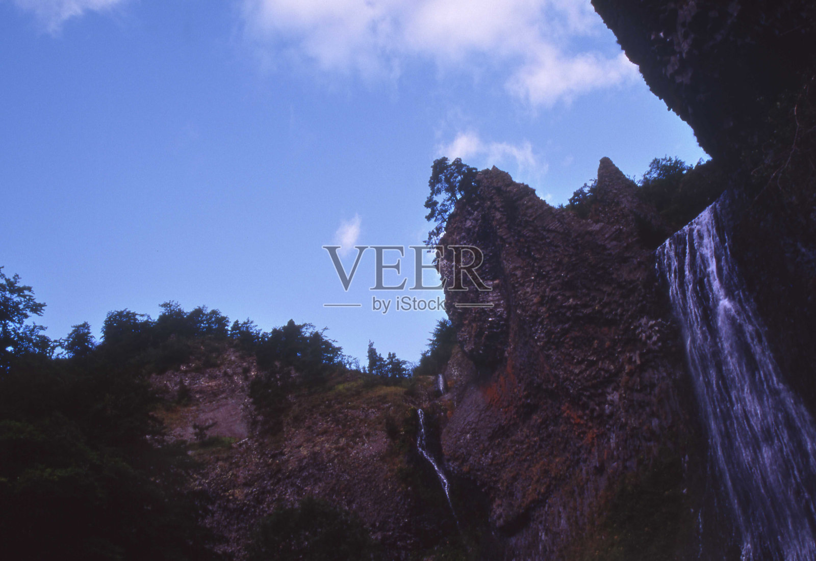 瀑布落在岩石和野生树木的右侧照片摄影图片