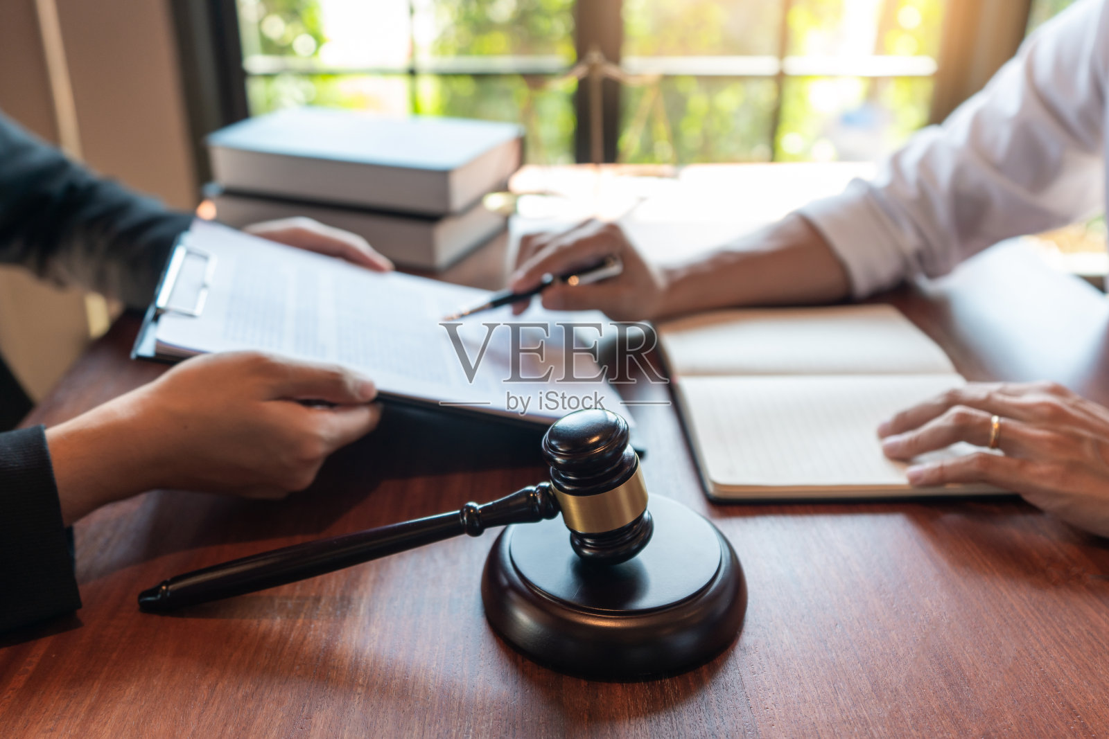 律师与客户在法庭上讨论有关法律法规的合同文件，为客户提供咨询帮助。照片摄影图片