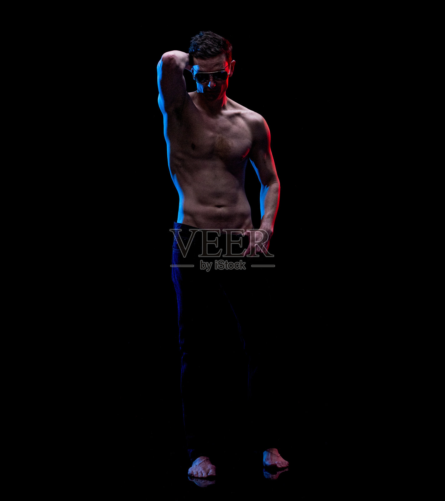 白人年轻男性穿着牛仔裤站在黑色背景前照片摄影图片