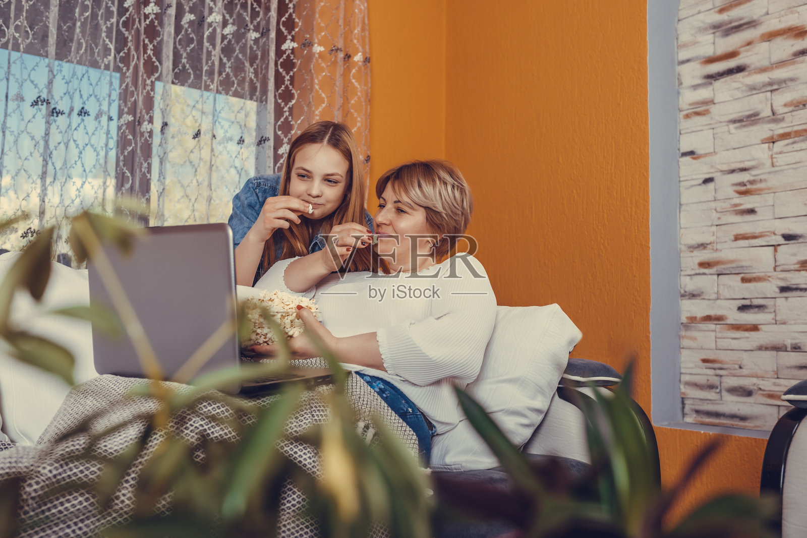妈妈和她十几岁的女儿一边看电影一边吃爆米花照片摄影图片