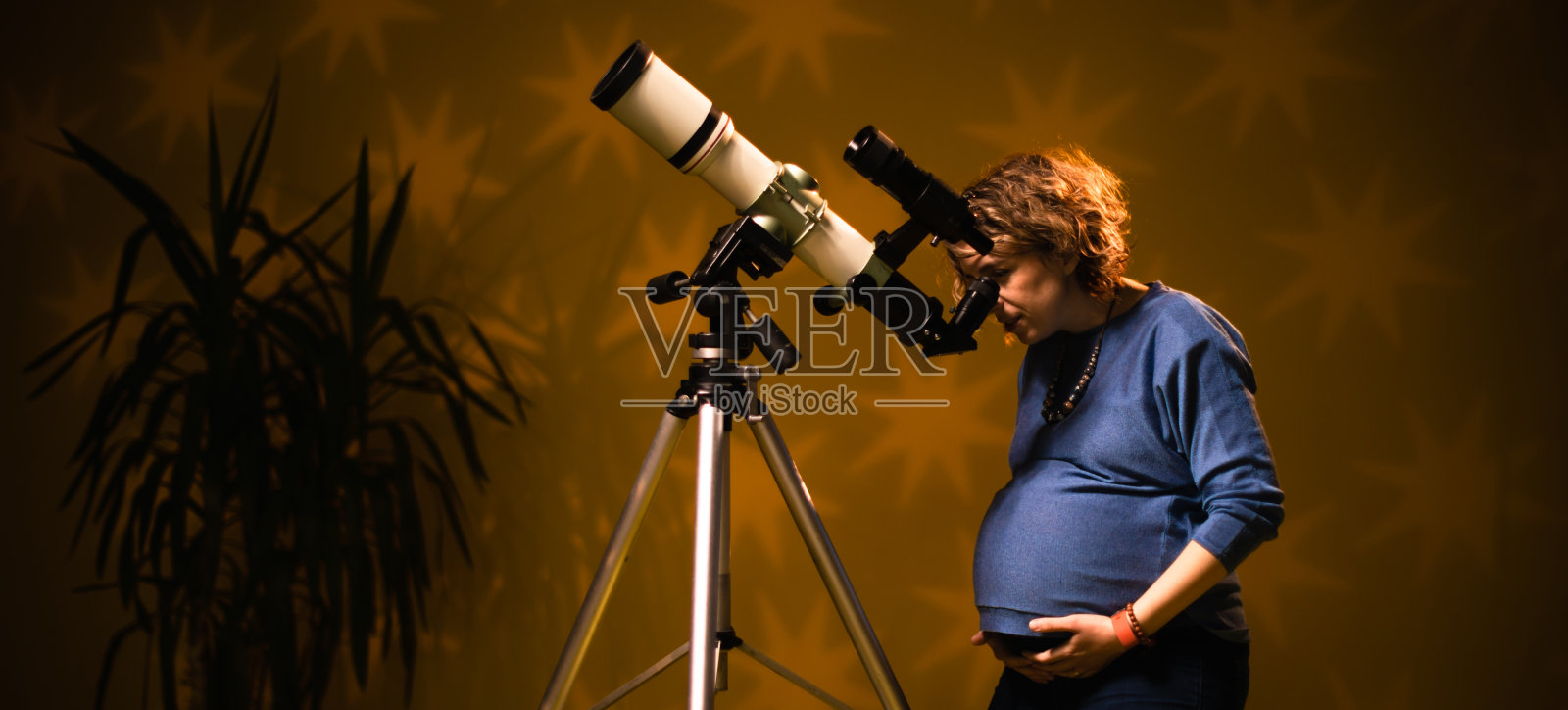 孕妇通过望远镜看星星——占星术的概念，占星术预测胎儿。照片摄影图片