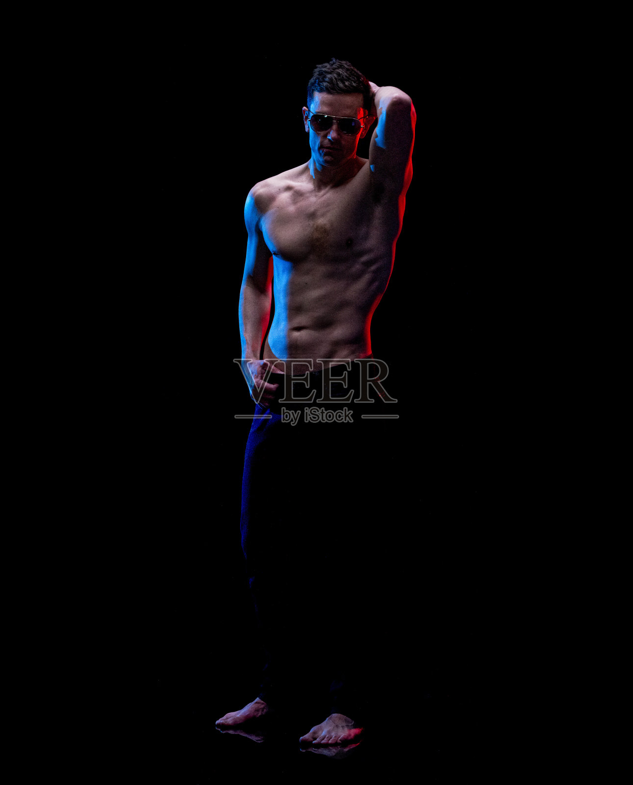 白人年轻男性穿着牛仔裤站在黑色背景前照片摄影图片