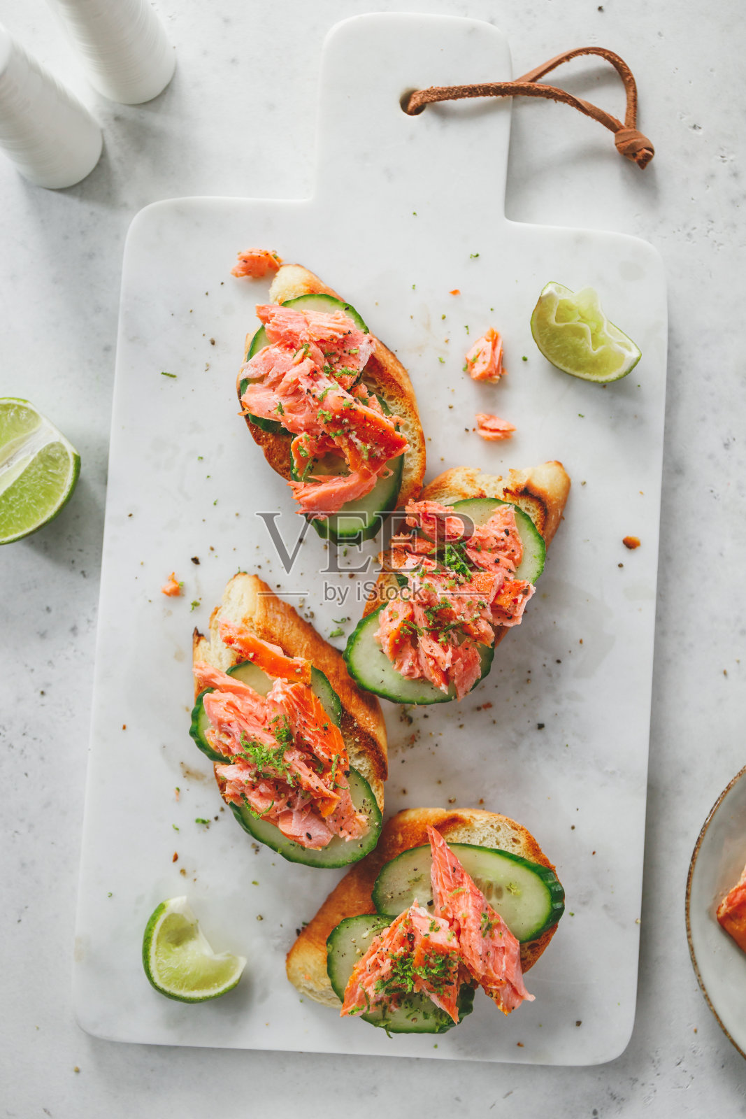 新鲜黄瓜和烟熏鲑鱼配青柠片烤面包。照片摄影图片