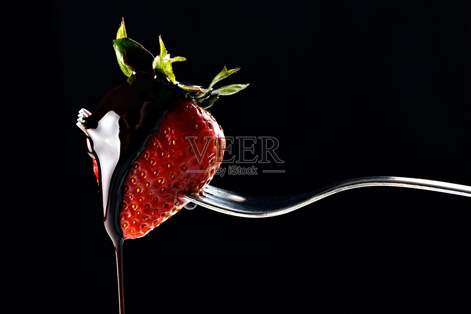 草莓被叉扎了一下。照片摄影图片