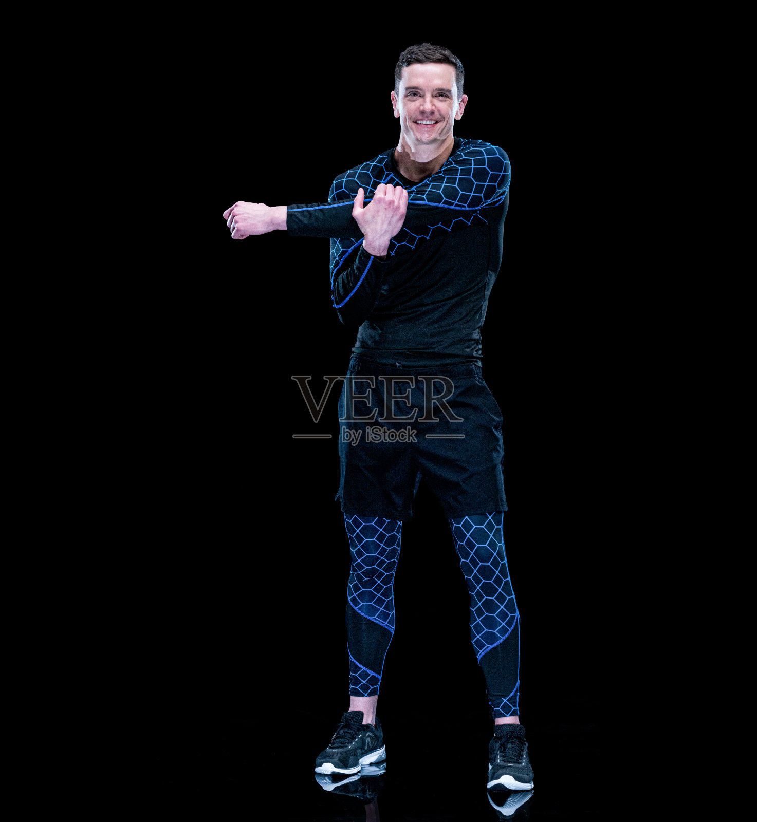 白人年轻男性运动员伸展在黑色背景穿着紧身裤照片摄影图片