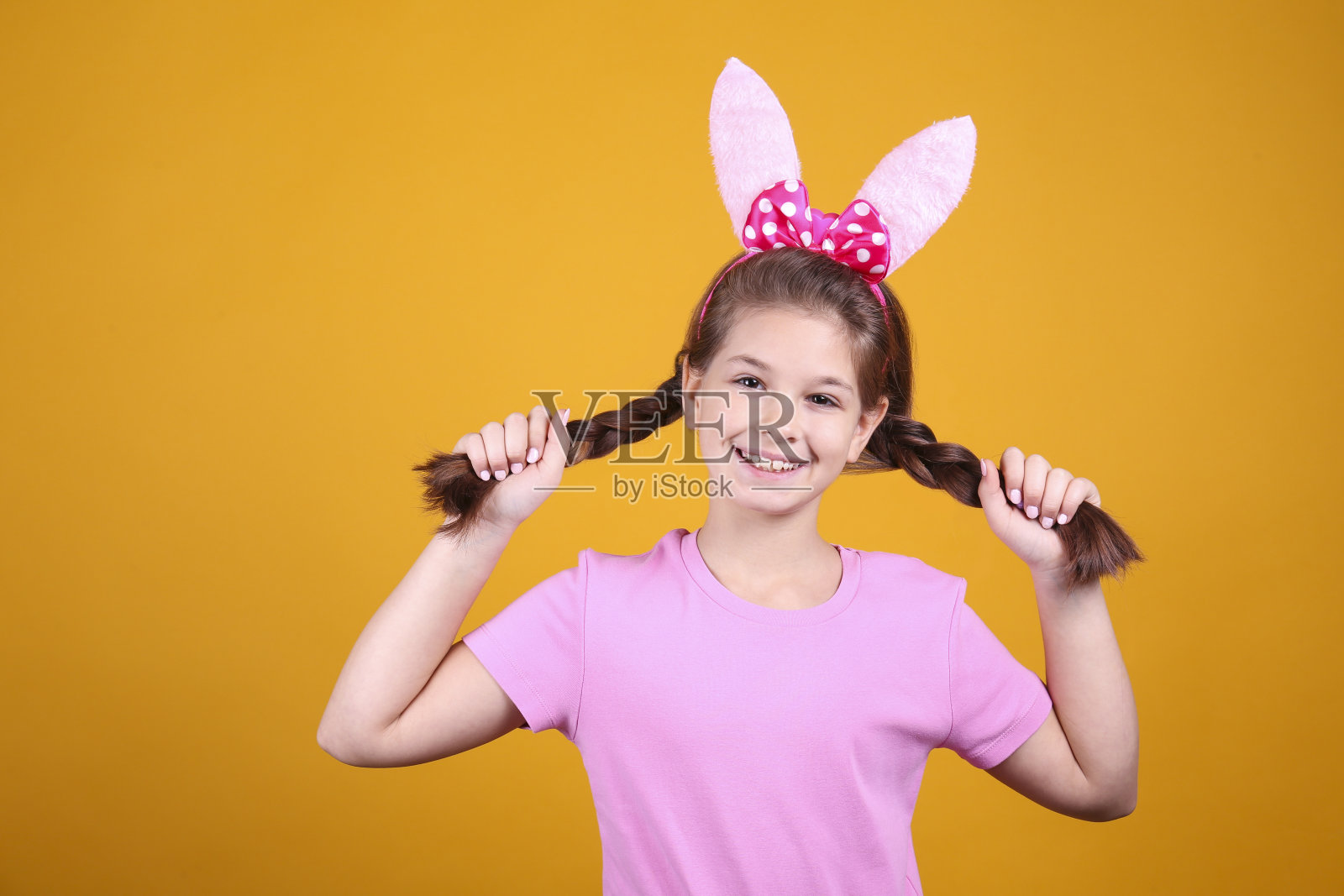 一个女孩戴着兔子耳朵庆祝复活节的概念形象。照片摄影图片