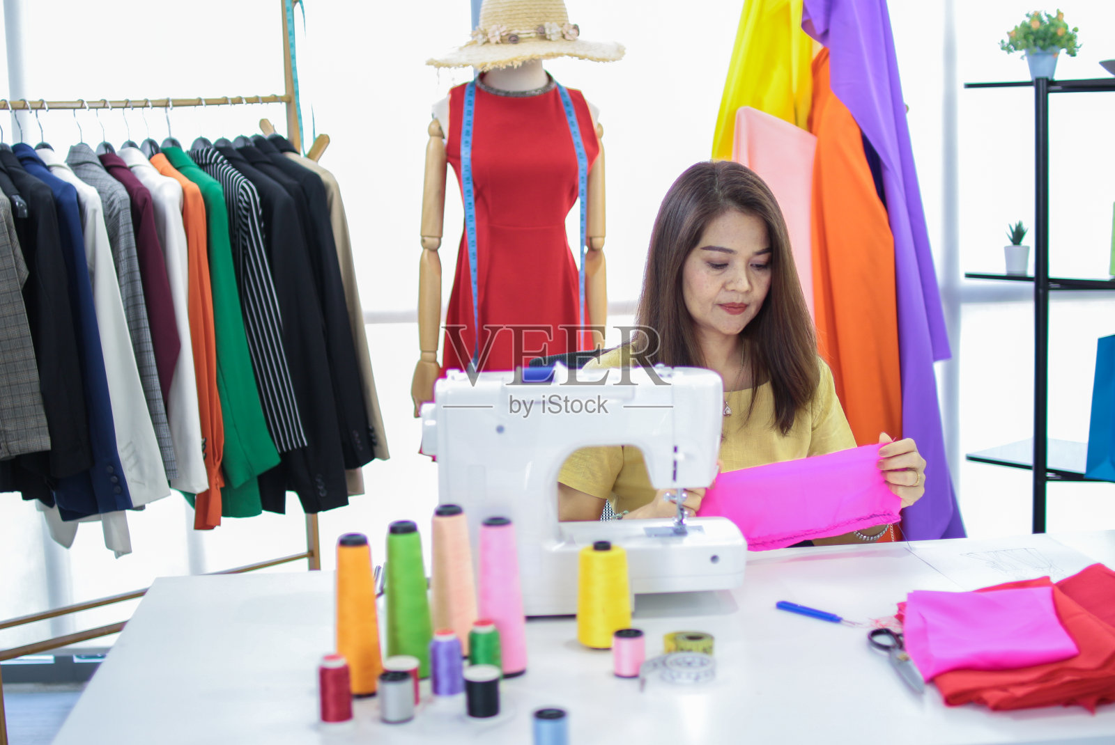 快乐微笑的亚洲创意时装设计师正在工作的业主，裁缝，裁缝店。亚洲女企业家看着相机站在商店里照片摄影图片