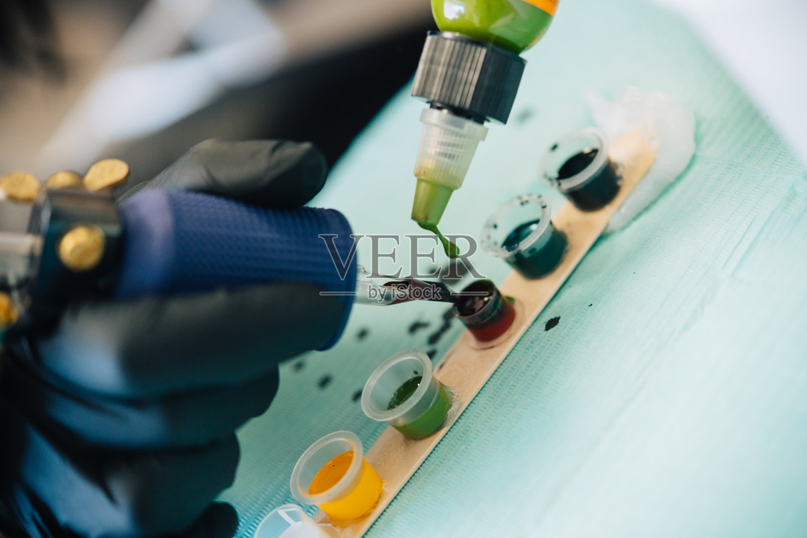 女纹身师往纹身机里装墨水。照片摄影图片