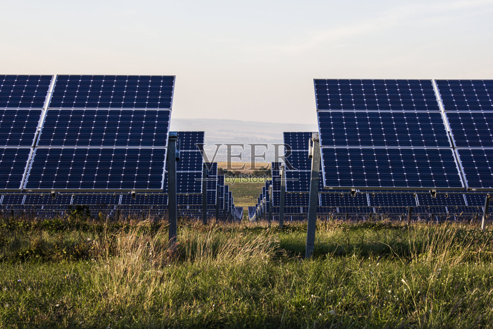 夕阳背景上的光伏电池。发电厂使用可再生的太阳能与多云的蓝天。行业及经营理念照片摄影图片