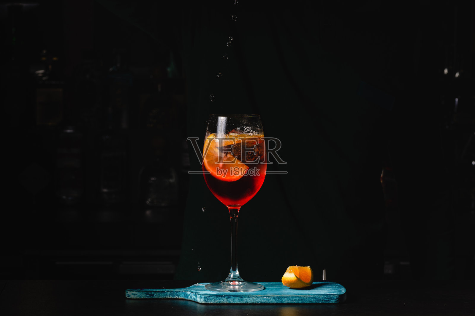 调酒师倒起泡酒与Aperol鸡尾酒。黑色背景照片摄影图片