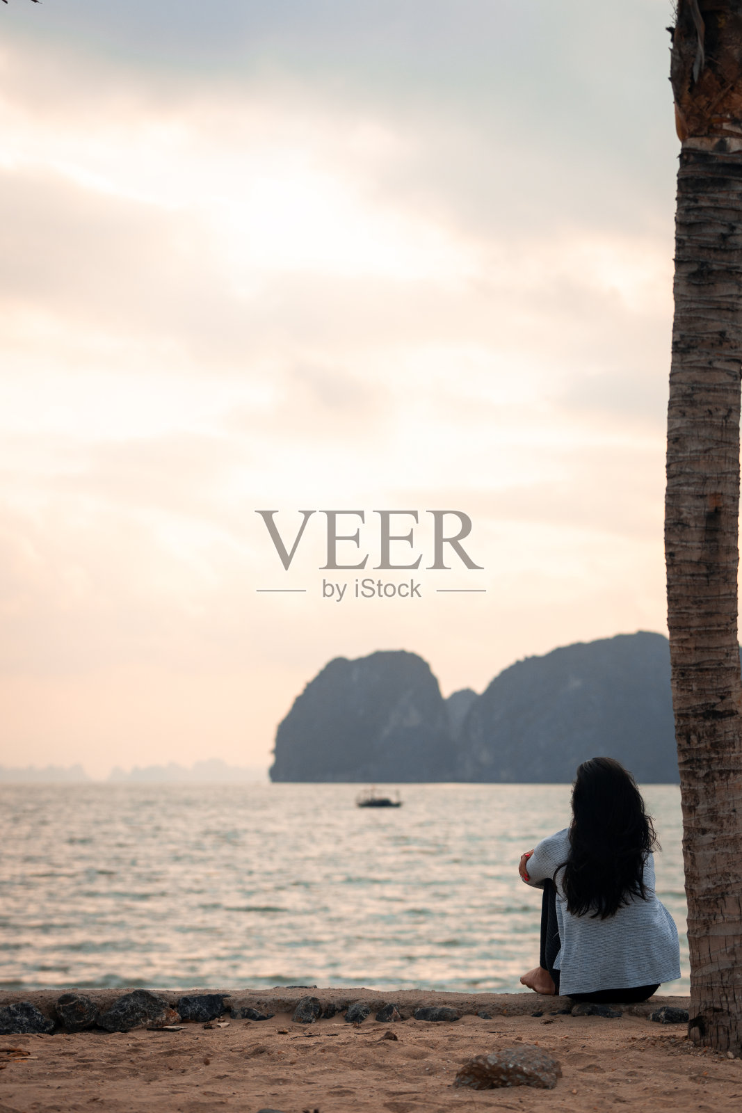 妇女们坐在海滩上欣赏下龙湾的日出照片摄影图片