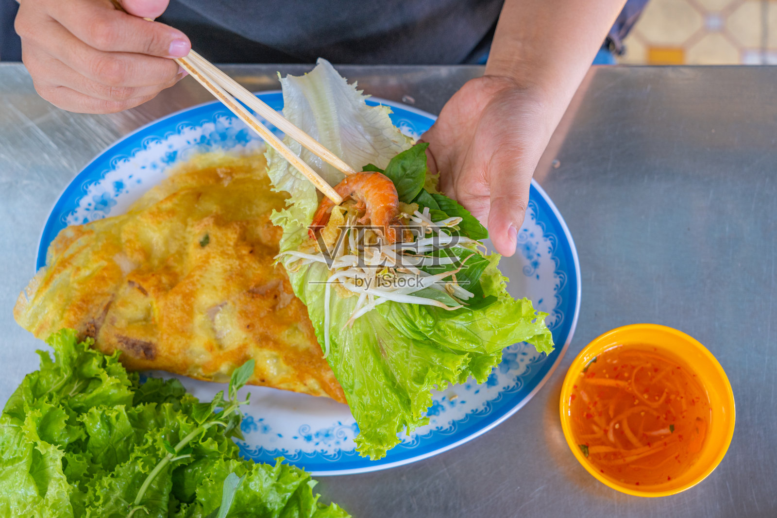 游客品尝越南美食——越南薄饼配新鲜蔬菜照片摄影图片