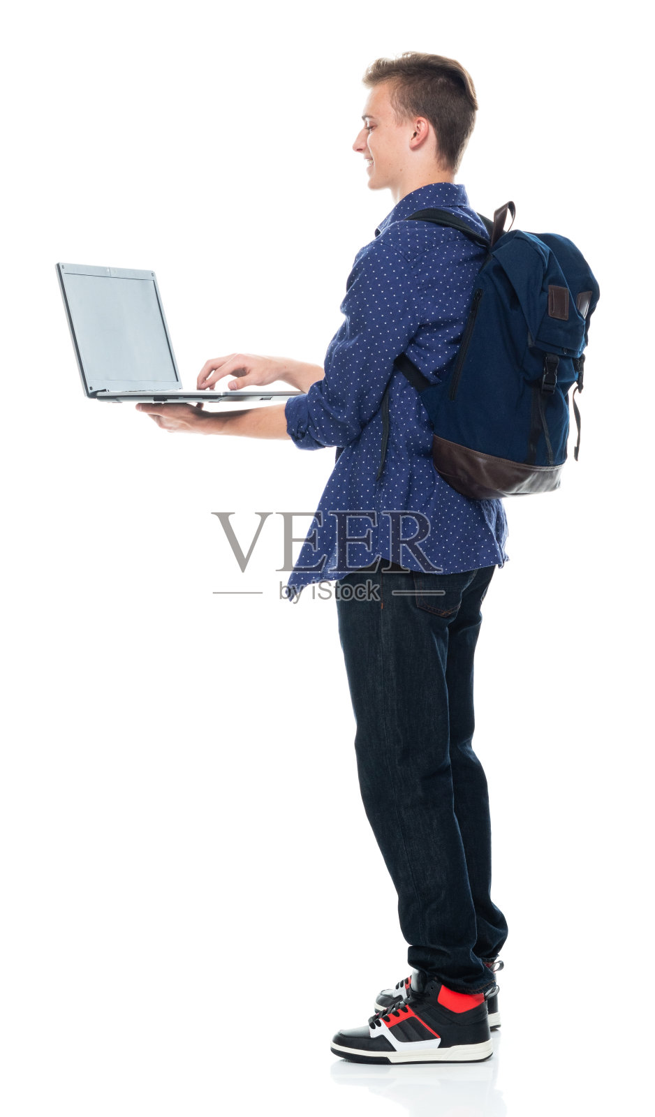 站在白色背景前，穿着纽扣衬衫，使用笔记本电脑的白人男子照片摄影图片