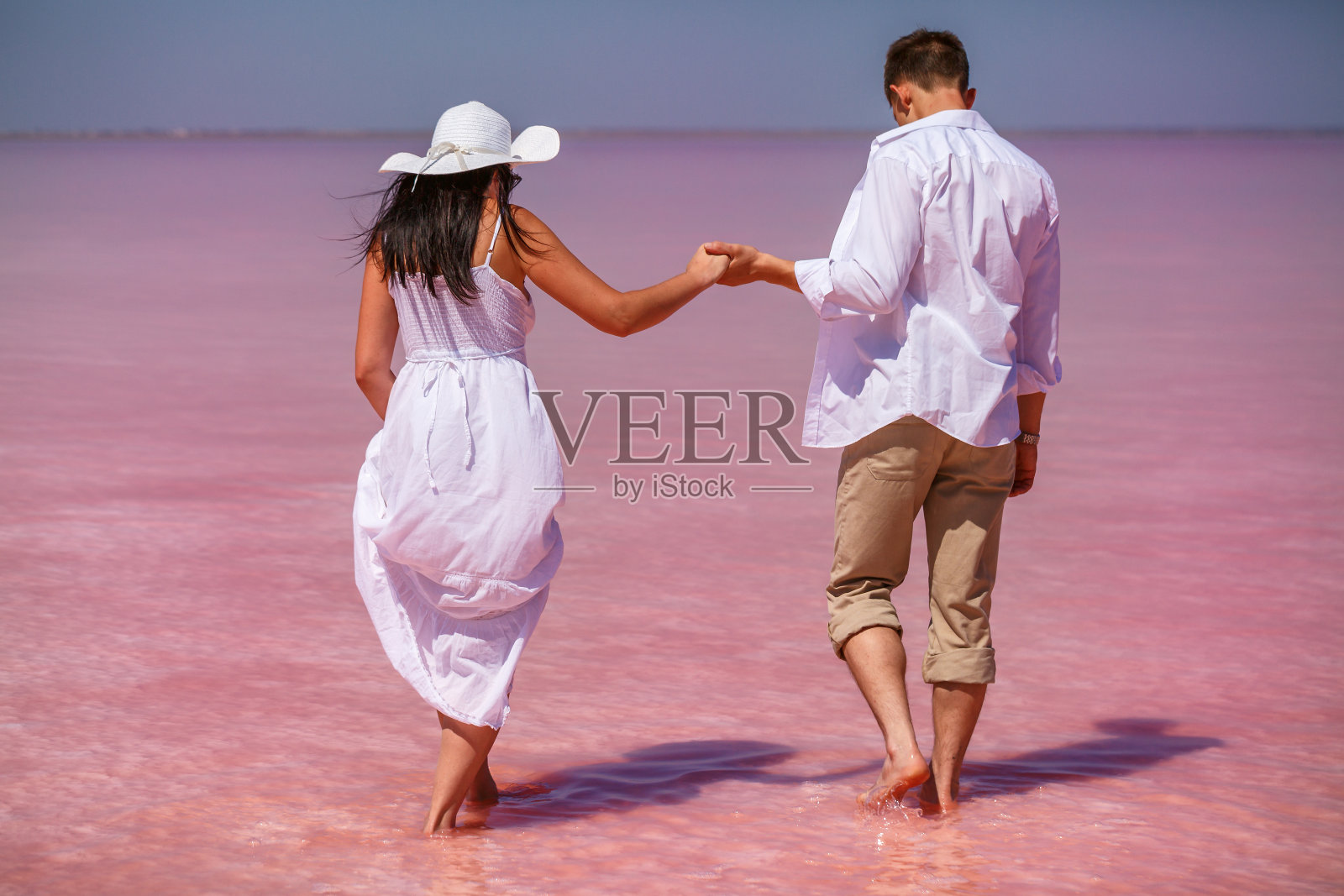 一个穿着白色衣服的男人和一个女人在一个咸咸的粉红色的湖上照片摄影图片