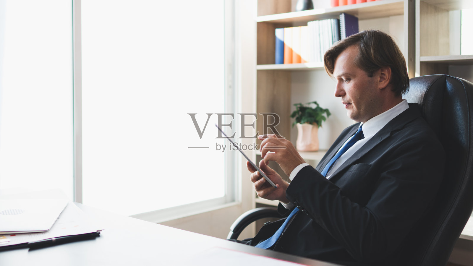 专业的商人专注和培养低头看他的写字板在旁边的窗口，复印空间在左边，概念沉思的雇主，成功的企业家。照片摄影图片