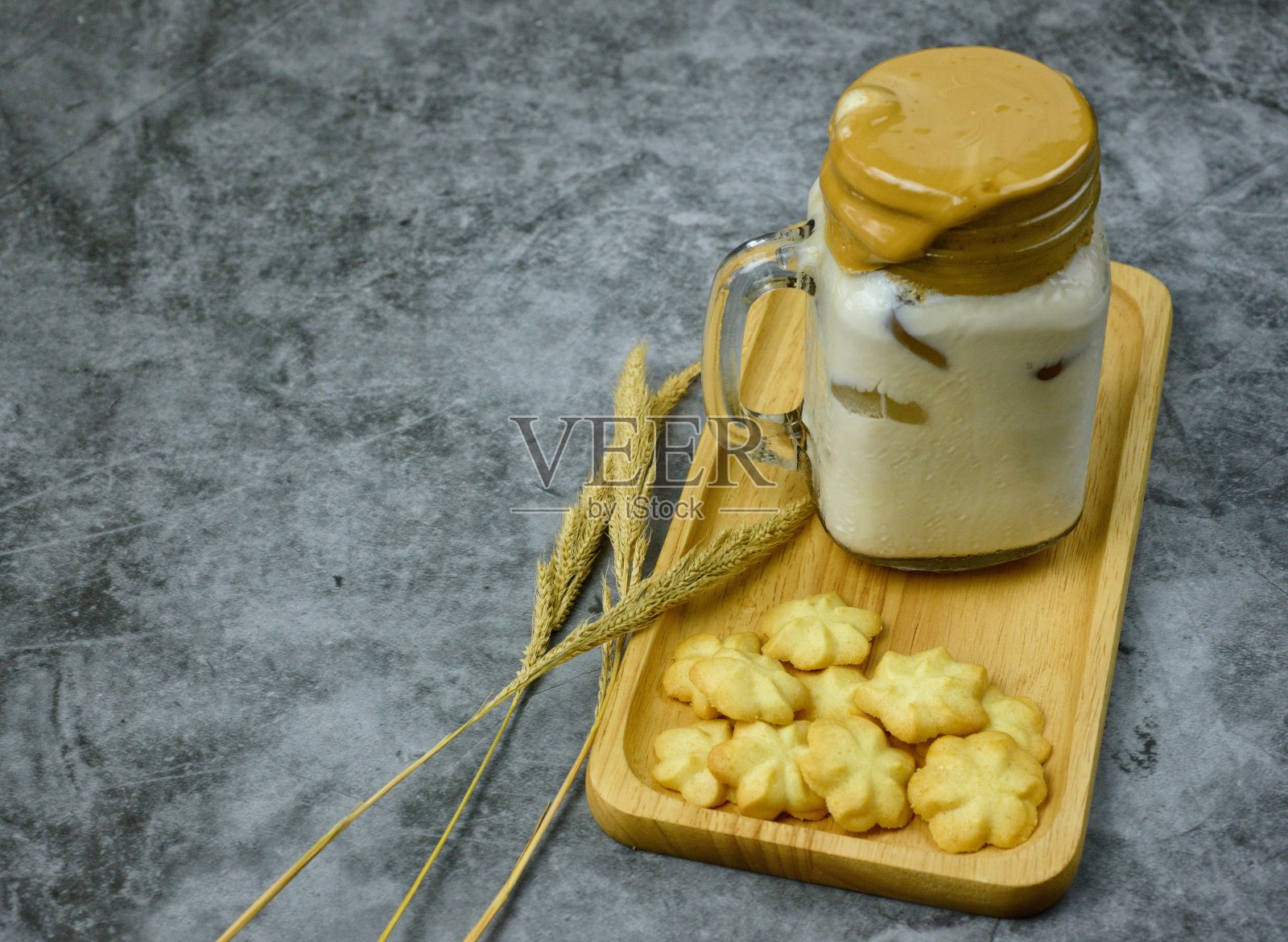 奶油牛奶曲奇和美味可口的饮料放在木制托盘上，供休闲和需要甜点的消费者享用，在吃的同时放松心情。照片摄影图片