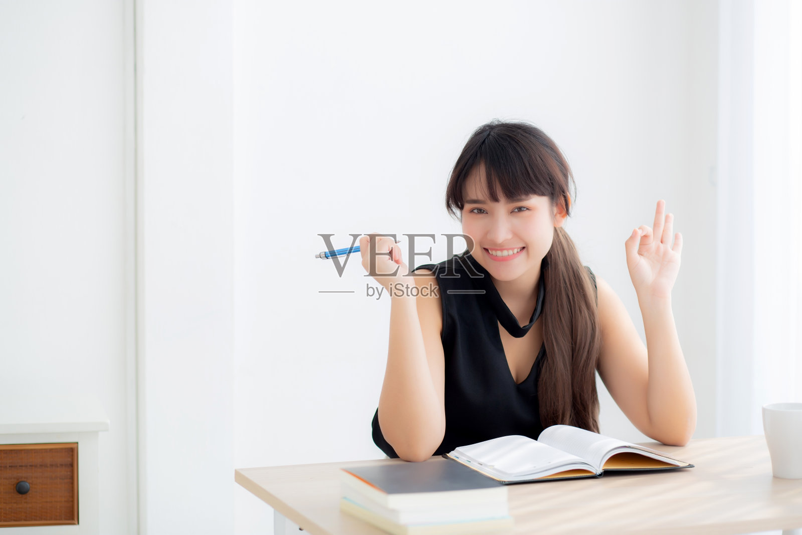 美丽肖像年轻的亚洲妇女坐在学习和学习写笔记本和日记在家里的客厅，女孩作业，商业妇女工作在桌子上，教育理念。照片摄影图片