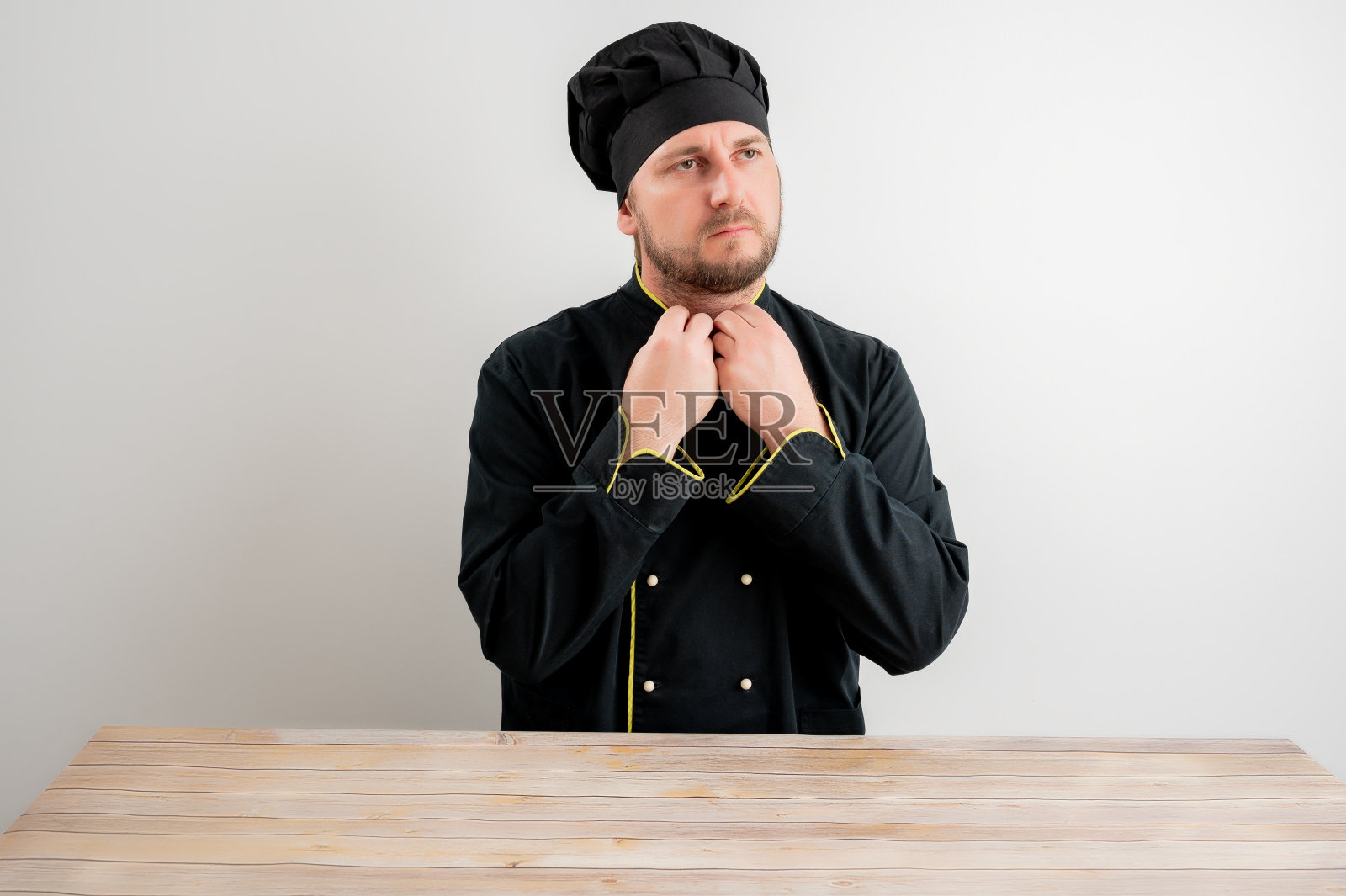 穿着黑色制服的年轻男厨师整理着他的衣领照片摄影图片