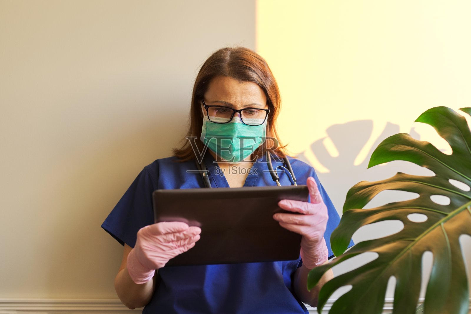 严肃的女医生戴着防护口罩，戴着手套读数码平板电脑照片摄影图片