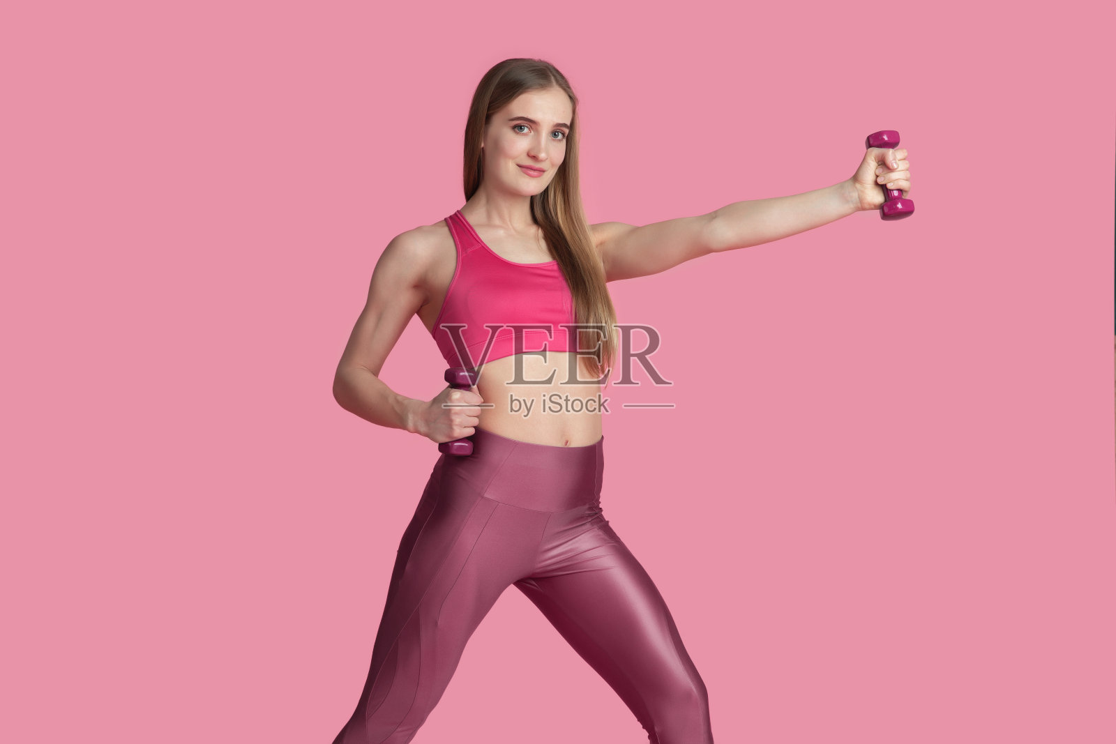 美丽的年轻女运动员练习在粉红色的工作室背景，单色肖像照片摄影图片
