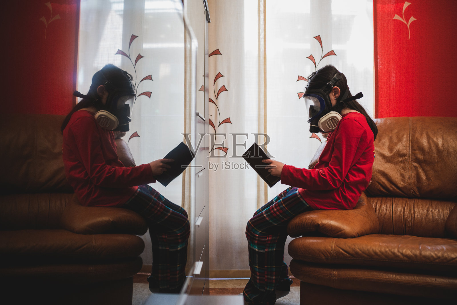 孩子戴着口罩在家看书。照片摄影图片