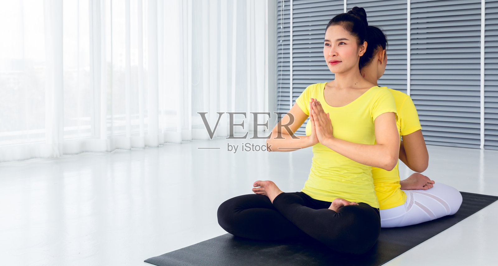两位美丽的亚洲女性在瑜伽室里练习瑜伽，以保持身体健康和肌肉的灵活性，并感觉良好和幸福。这是一种对每个人都有益的生活方式活动。照片摄影图片