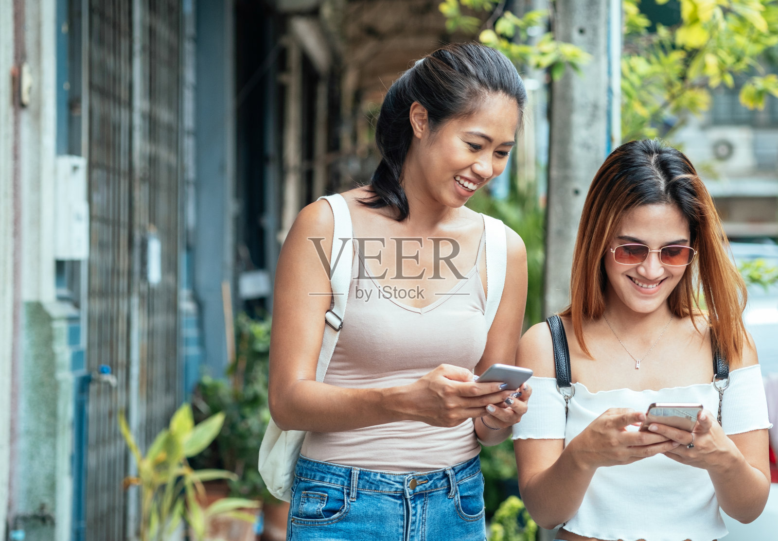 两个快乐的朋友在看智能手机和微笑的库存照片照片摄影图片