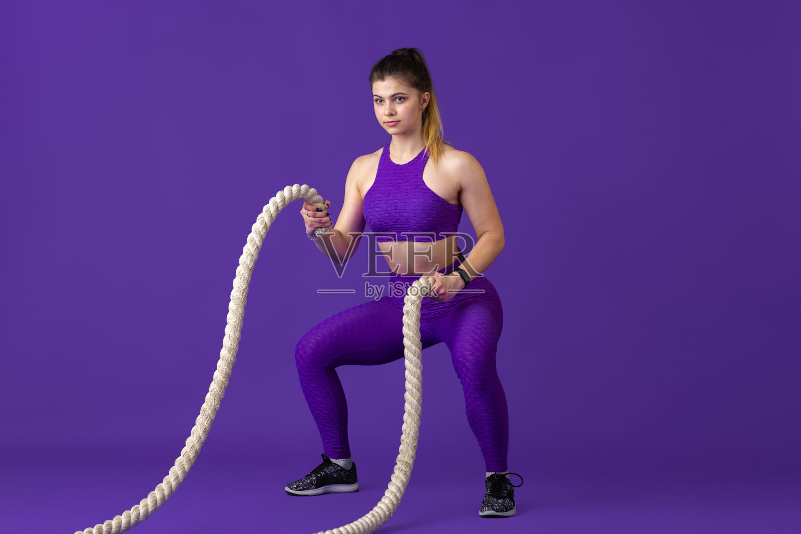 美丽的年轻女运动员练习在紫色的工作室背景，单色肖像照片摄影图片