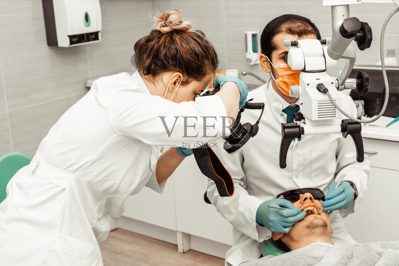 两个牙医给一个病人看病。牙医的专业制服和设备。医疗设备doctorâ的工作场所。牙科照片摄影图片
