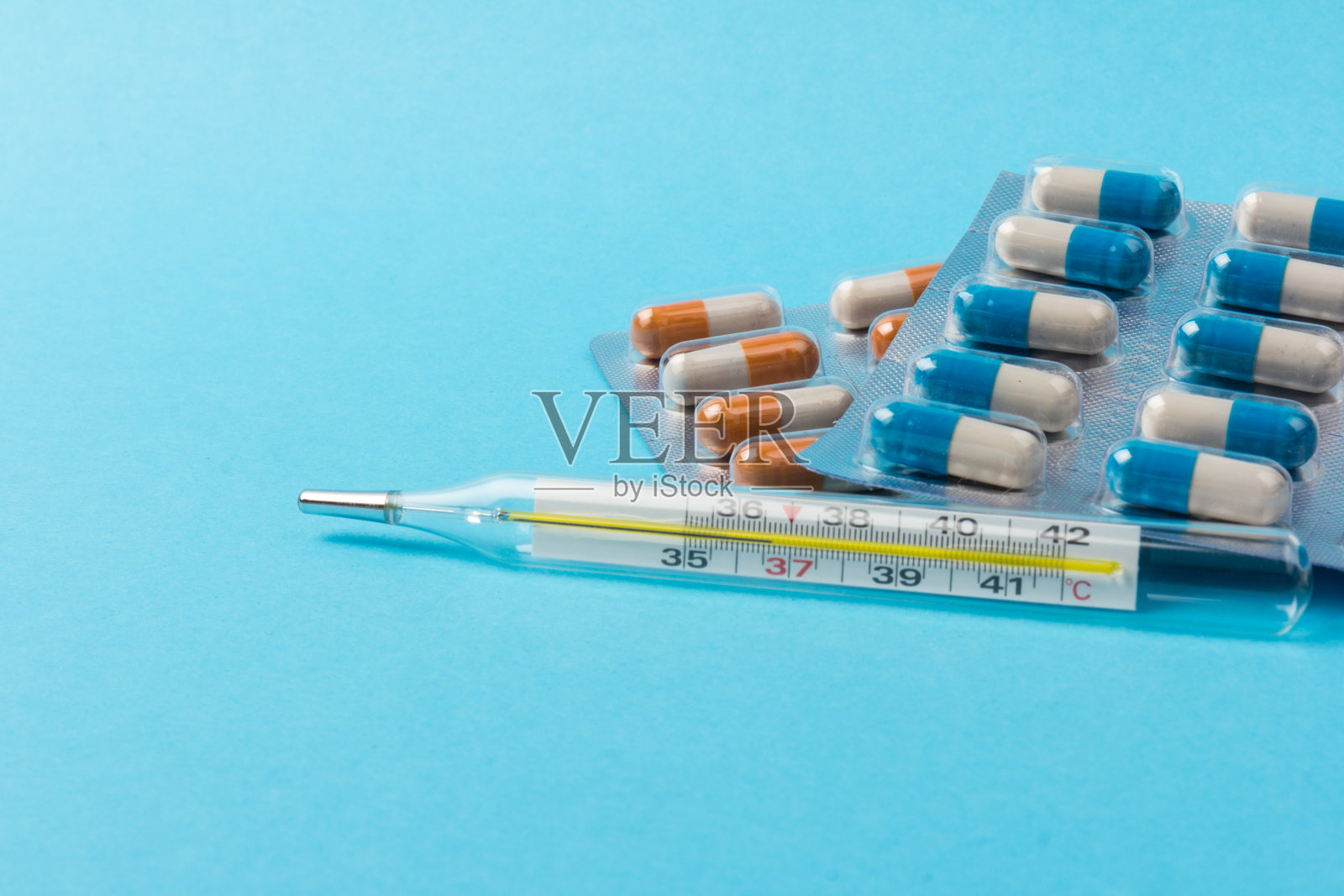 不同的药片用温度计，药片用铝箔泡罩包装，药物用蓝色背景照片摄影图片