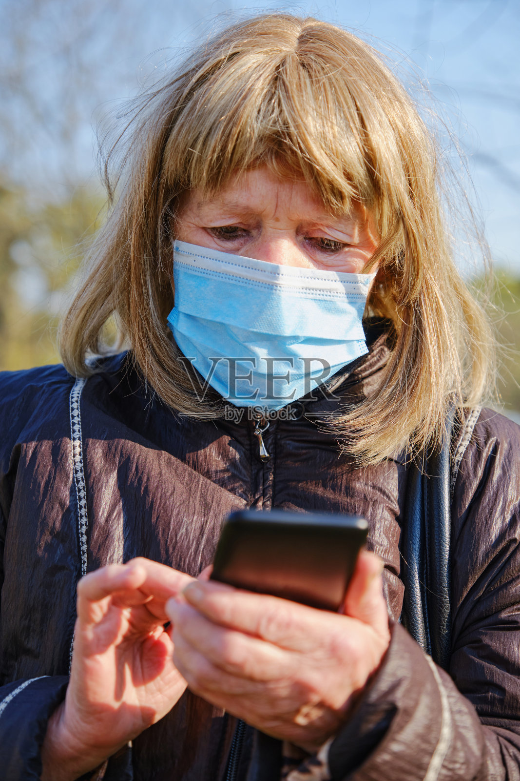 白种老年妇女戴口罩保护新冠肺炎疫情，使用智能手机与家人交谈照片摄影图片