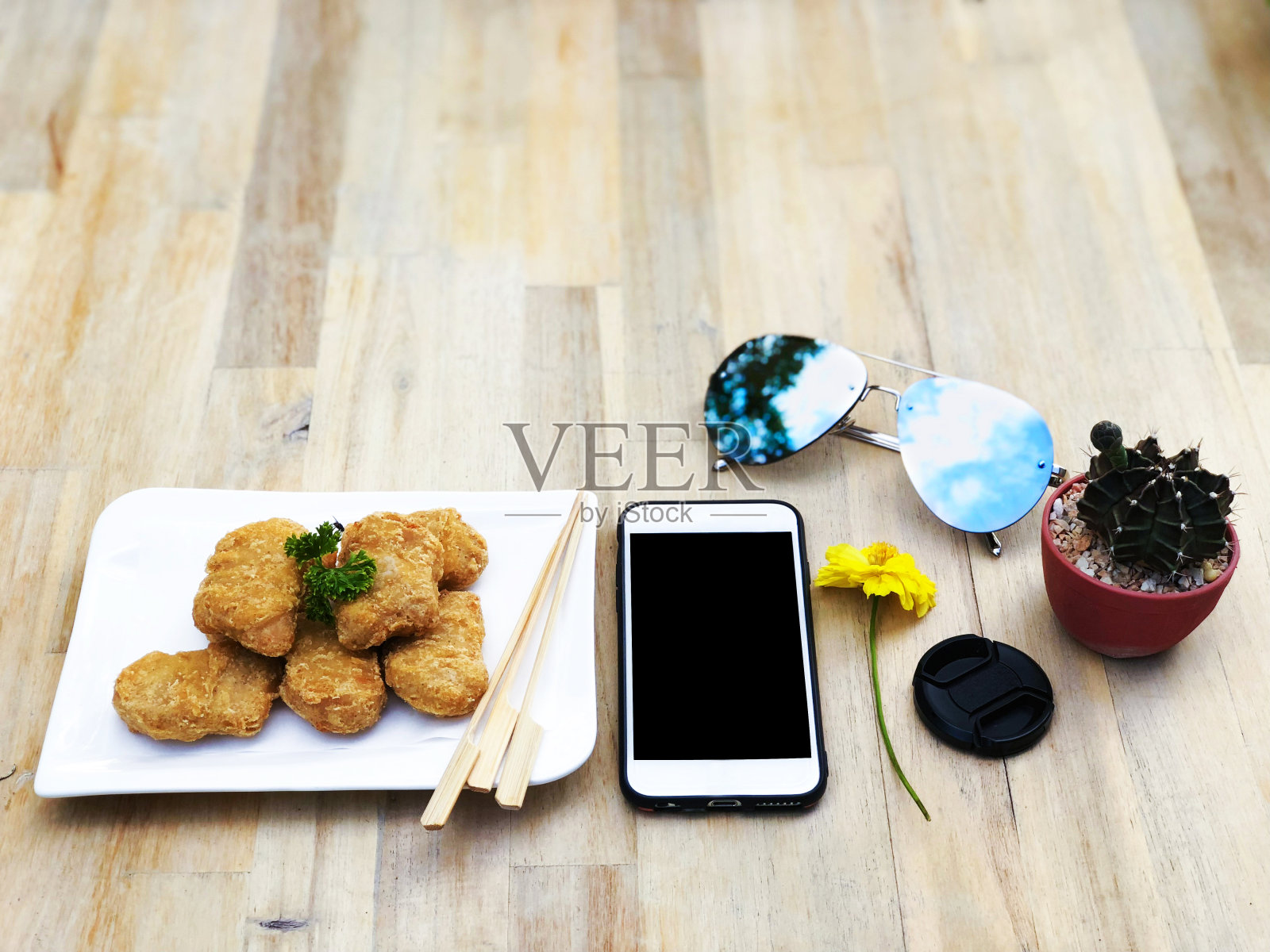 休息时间与零食餐，鸡块开胃菜吃在寒冷的一天时间，与手机，太阳镜和仙人掌花孤立在木桌子的背景，选择性焦点顶视图。照片摄影图片